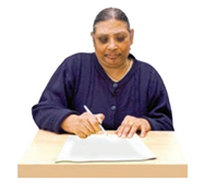 Complete A woman sat at a desk with some paper in front of her. She is writing on the paper.